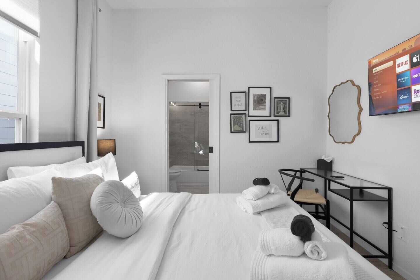 Habitación de hotel moderna con una cama bien hecha, un escritorio con silla y un televisor mostrando servicios de streaming.