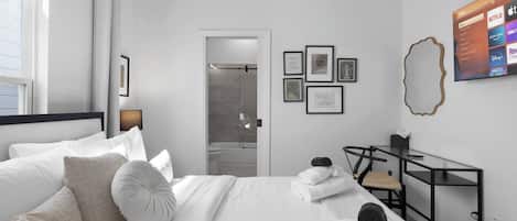 Habitación de hotel moderna con una cama bien hecha, un escritorio con silla y un televisor mostrando servicios de streaming.