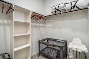 A walk-in closet with open shelves, a baby changing station, and a baby high chair. - NRG Access | Sleeps 10 | Near The Heights (Houston)