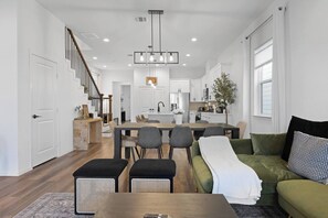 A modern kitchen with white cabinets, a central island, and pendant lighting. - NRG Access | Sleeps 10 | Near The Heights (Houston)