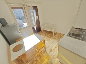 Eine kleine Küche mit Spüle, einem weißen Tisch und einer Bank.