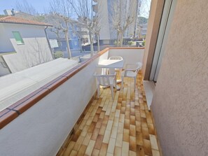 A balcony with a tiled floor, a small table, and two chairs. - Apartment close to sea and centre (Lignano Sabbiadoro)