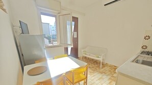 A compact kitchen with a dining area, a bench, and a window. - Comfortable stay near beach (Lignano Sabbiadoro)