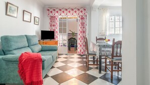 A living room with a sofa, television, and a dining area with a table and chairs. - Paqui 1A Apartment - Families Only (Conil de la Frontera)