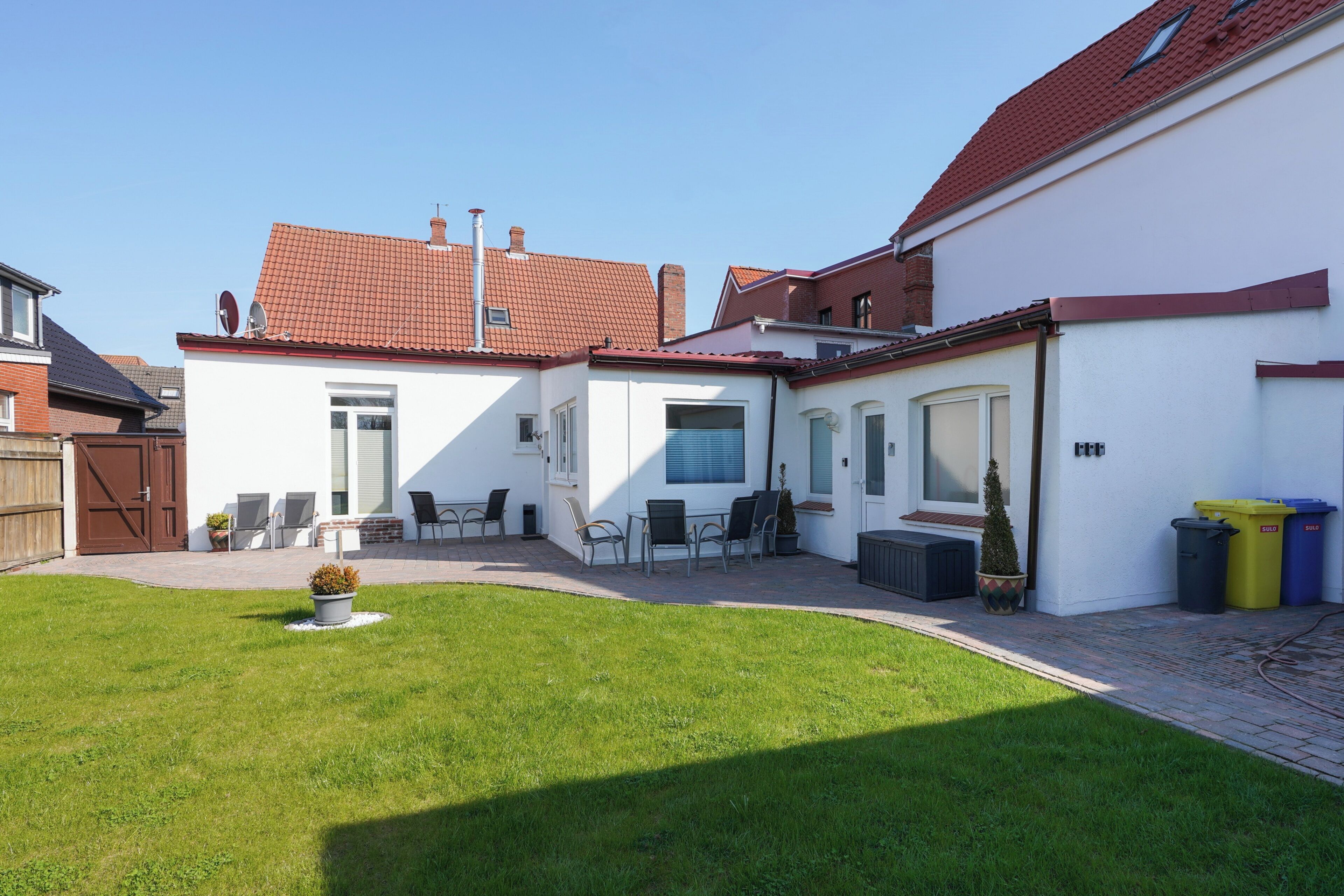 Een woonhuis met terras, tuinmeubilair buiten en een verzorgd gazon.