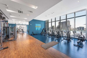 Ein Fitnessstudio mit Trainingsgeräten, einer blauen Wand mit motivierenden Texten und großen Fenstern.