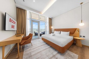 Ein modernes Hotelzimmer mit Bett, Schreibtisch, Stuhl und einem Schild mit der Aufschrift 'BOOK ME'.