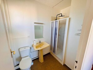 Une salle de bain comprenant des toilettes, un lavabo, un miroir et une douche.