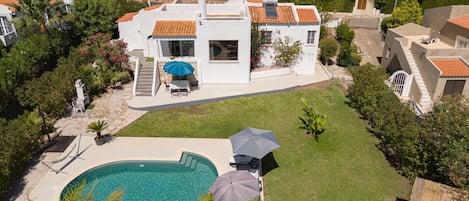 A residential property with a swimming pool, outdoor seating, and a well-maintained garden.