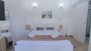 Una camera d'albergo con un letto grande, due comodini, un quadro al muro e una porta alla destra.