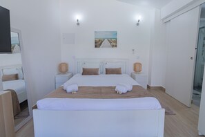 Ein Hotelzimmer mit einem großen Bett, zwei Nachttischen, einem Bild an der Wand und einer Tür rechts.