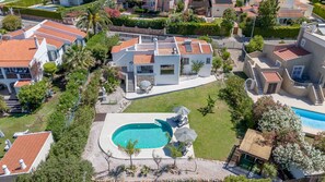 Eine Vogelperspektive eines Wohngebiets mit Swimmingpool, mehreren Häusern und gepflegten Gärten.