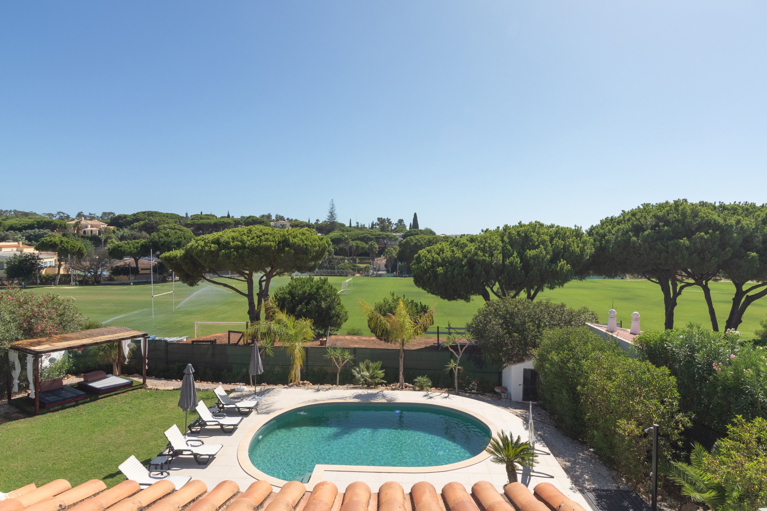 Une piscine avec des chaises longues et vue sur un terrain de golf.