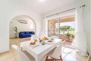 Ein Essbereich mit einem für das Frühstück gedeckten Tisch, einem blauen Sofa und Blick durch eine Glastür.