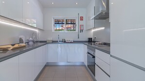 Una cucina moderna con mobili bianchi, un lavello in acciaio inossidabile e una finestra vista edifici.