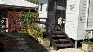 Uma casa térrea com varanda frontal, porta de correr de vidro e um pequeno lance de degraus até a entrada.