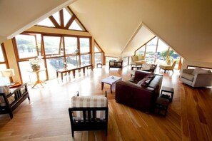 A spacious loft-style room with high ceilings, large windows, and a view of a body of water. - Inishbofin House Hotel (Inishbofin)