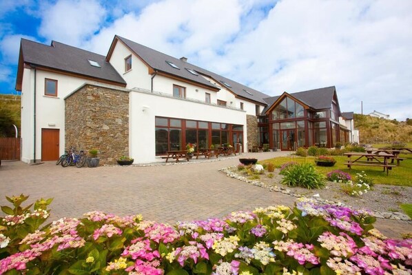 A modern building with a stone facade, large windows, and outdoor seating areas. - Inishbofin House Hotel (Inishbofin)