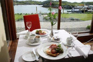 A table set for breakfast with a view of a lake and boats. - Inishbofin House Hotel (Inishbofin)
