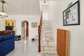 Eine Treppe mit einem hölzernen Geländer, einem gerahmten Notausgangsschild und einem gerahmten Hinweisschild an der Wand.