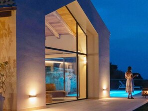 A modern building with large glass doors, a pool, and a person standing by the pool. - Villa With Private Pool and Sea View (Briatico)