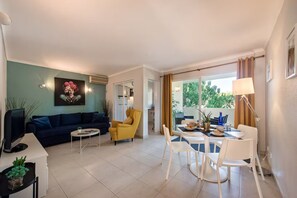 Ein modernes Wohnzimmer mit einer Couch, einem gelben Sessel, einem Esstisch und Stühlen.