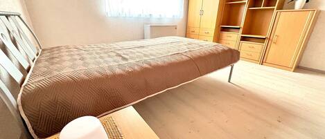 A room with a bed, a desk, and a wardrobe.