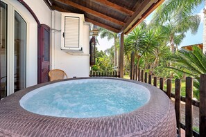 Un bain à remous bordé d'osier, une terrasse en bois et une clôture en bois.