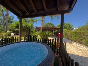 A hot tub under a wooden pergola with a view of palm trees and a gazebo in the background. - Typical Salento Villa on the Coast with Jacuzzi (Santa Cesarea Terme)