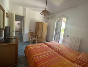 Una habitación con dos camas, un armario de madera, una silla, un escritorio con un ordenador y un espejo.