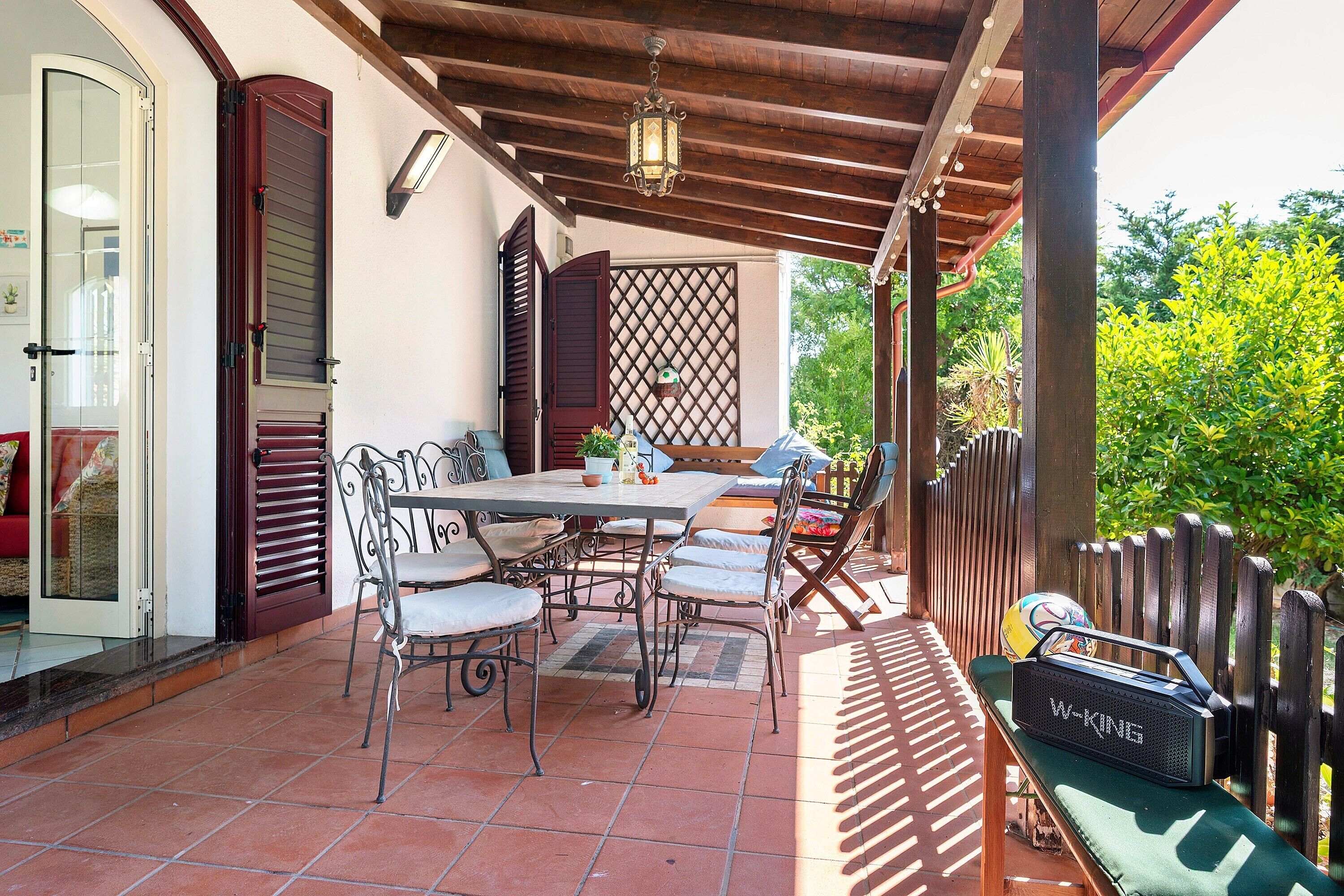 Eine Terrasse im Freien mit Tisch und Stühlen, einer Holzhütte und einem Lautsprecher.