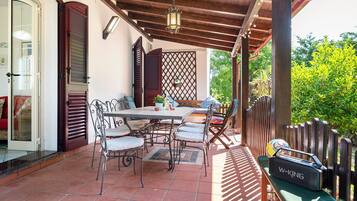 Eine Terrasse im Freien mit Tisch und Stühlen, einer Holzhütte und einem Lautsprecher.