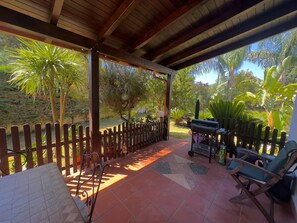Un patio al aire libre con una pérgola de madera, una parrilla y un área de estar con mesa y sillas.