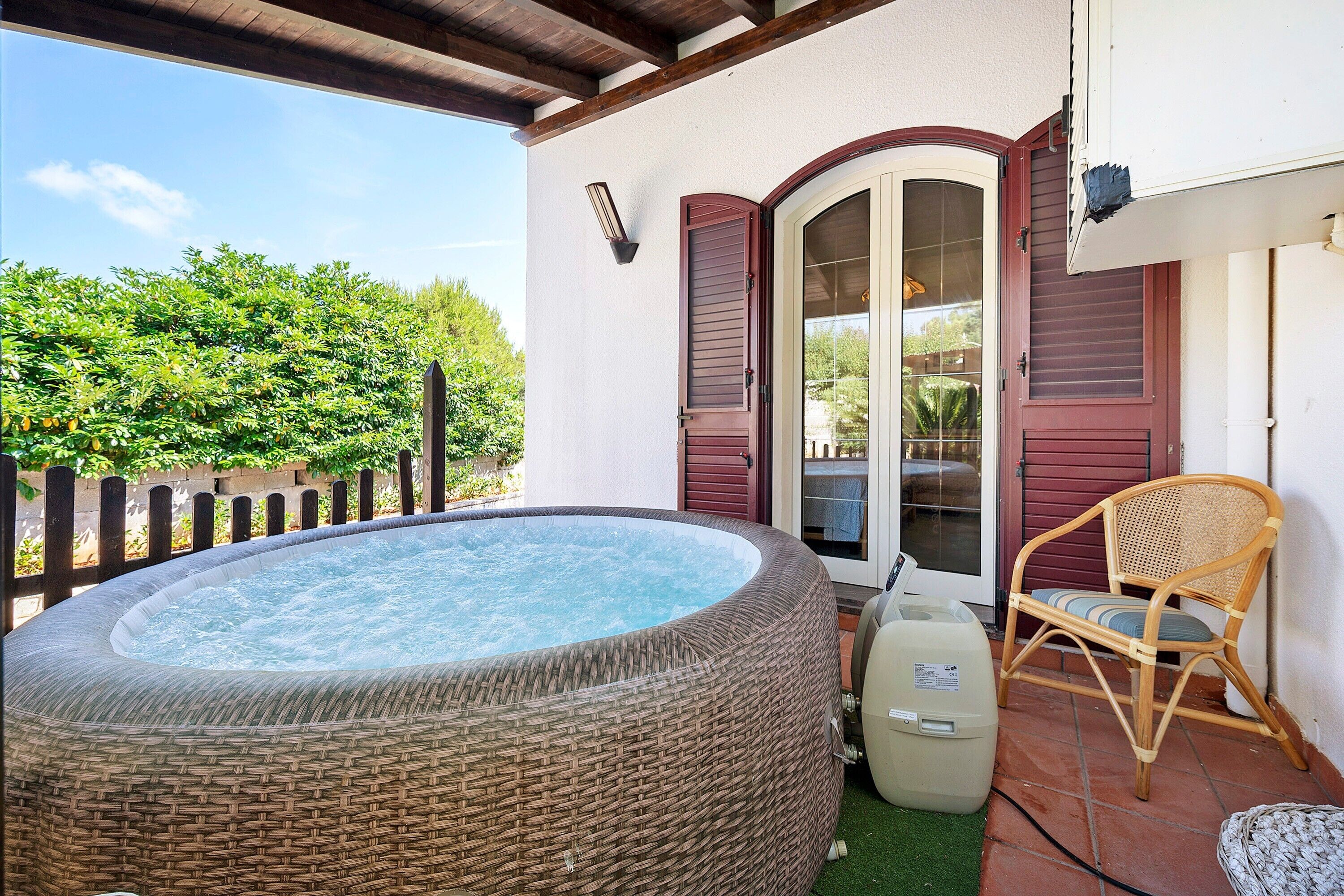 A hot tub, wicker chair, and a door with glass panels.