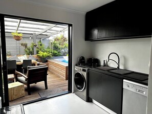 A compact kitchen with a washing machine, a sink, and a small dining area with a table and chairs. - Hot Tub, Pet Friendly, Blouberg Retreat (Cape Town)