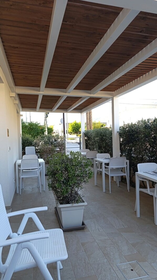 An outdoor patio with white furniture, a wooden ceiling, and a view of the street. - Butiko (Castelluzzo)