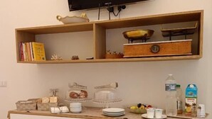 Eine moderne Küche mit Flachbildfernseher, Holzregalen, einer Kaffeestation und einem Esstisch mit einer Speiseplatte und einer Tasse.