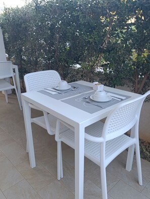 A white outdoor dining table with chairs, set with a teapot, cup, and saucer, and a small box of sugar cubes. - Butiko (Castelluzzo)