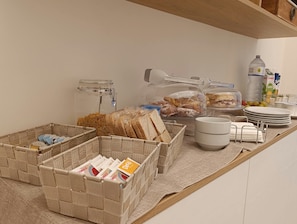 Ein reichhaltiges Frühstücksbuffet mit Brot, Gebäck und Getränken.