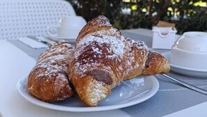 Ein weißer Tisch mit einem Teller Croissants und einer Tasse Kaffee.