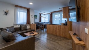 A modern living room with a sofa, a dining area, and a kitchen counter. - Maiskogelblick Apartments - TOP 3, Garden & Sauna (Piesendorf)