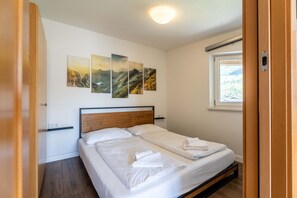 Ein Schlafzimmer mit Bett, Fenster und Wandbildern.