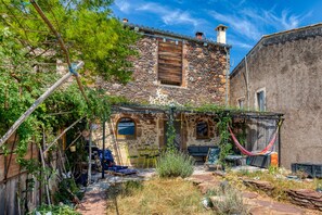 A stone building with a wooden door and a window. There is a hammock and a table with chairs outside. - Apartment "Les Trésors Du Lac" with Lake View, Wi-Fi and Air Conditioning (Celles)