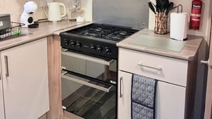 A kitchen with light-colored cabinets, a stove, oven, and a fire extinguisher.