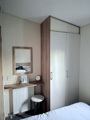 Ein Schlafzimmer mit einem Bett, einem Nachttisch, einem Spiegel, einer Heizung und einem Kleiderschrank.