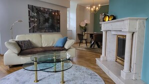 Una sala de estar con un sofá, una mesa de centro de vidrio, una chimenea y un comedor.
