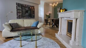 Ein Wohnzimmer mit Sofa, einem Glastisch, einem Kamin und einem Essbereich.