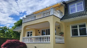 Ein zweistöckiges Haus mit Balkon, einer Uhr und einem Blumentopf.