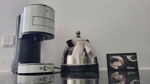 A coffee maker, a teapot, and a box of coffee pods on a table.