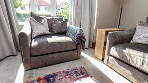 En stue med sofa, gulvtæppe og lampe.
